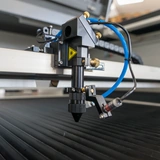 Catalogue reference close-up of a laser head, blue hose and slatted working bed